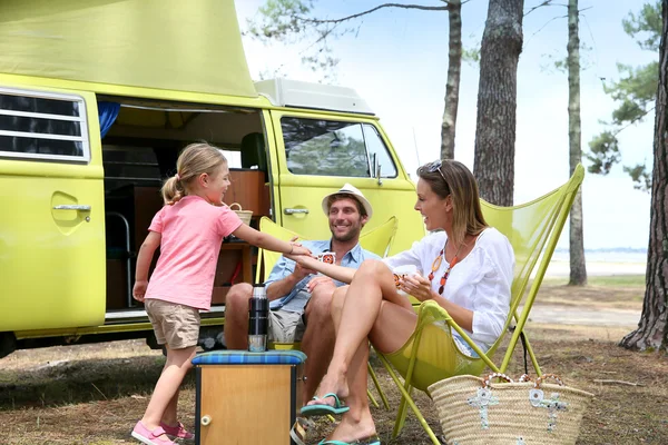 family relaxing by camper van in summer