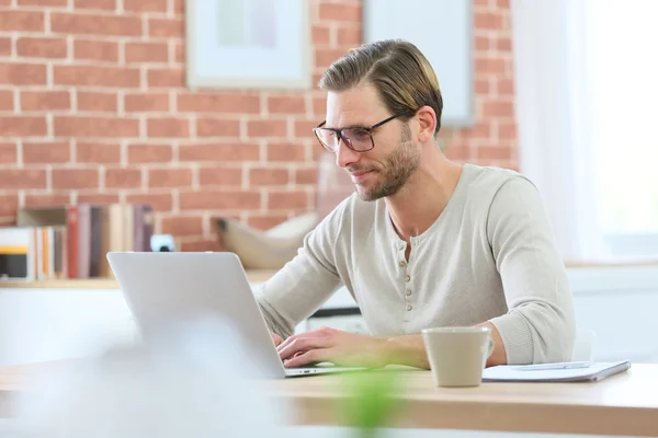 Mann sitzt vor Laptop-Computer lizenzfreie Stockfotos