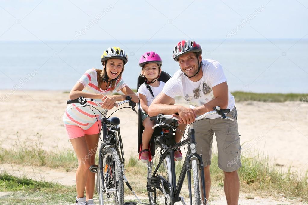 family riding bikes on a sandy path