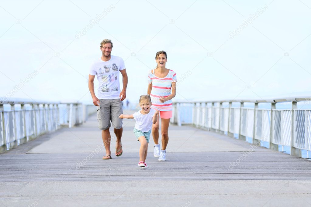 girl with parents running on a bridge