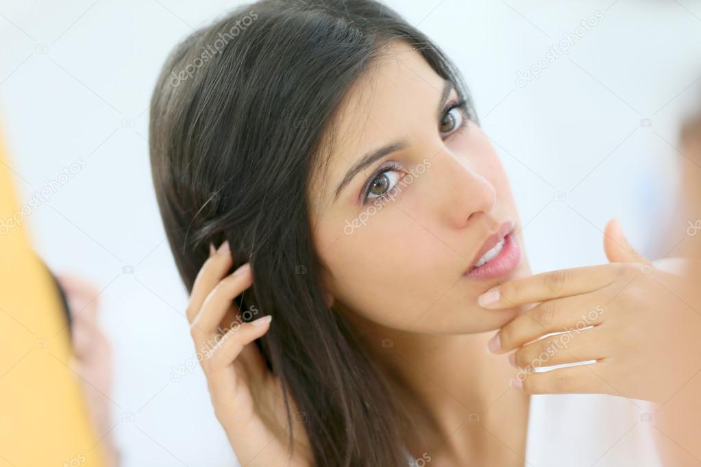 young woman looking at her skin
