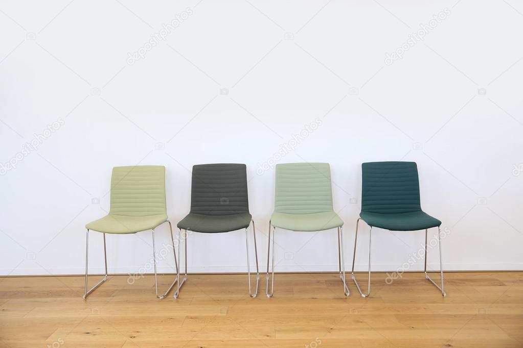 Row of chairs set against white wall