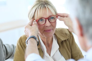 Senior woman trying new eyeglasses on clipart