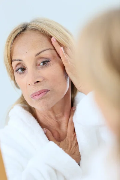 Oudere vrouw brengt gezichtscrème aan — Stockfoto