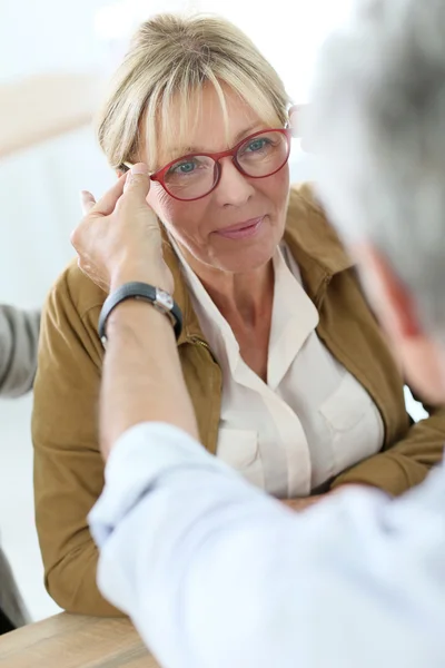 Senior woman trying new eyeglasses on — Stock Photo, Image