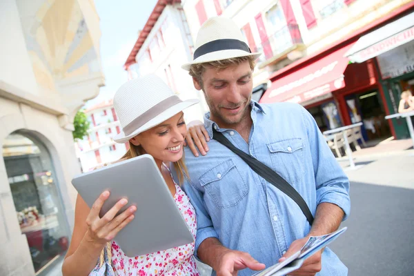 Couple in vacation looking at tourist guide — Stock Photo, Image