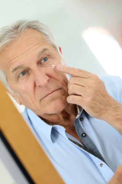 Senior man applying lotion — Stock Photo, Image