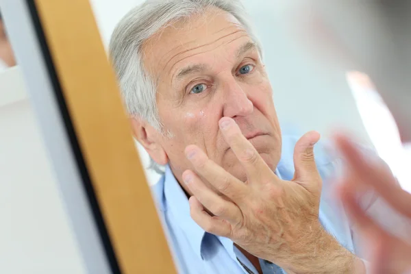 Man applying anti-aging lotion — Stock Photo, Image