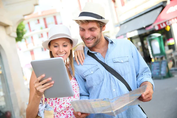 Couple in vacation looking at tourist guide — Stock Photo, Image