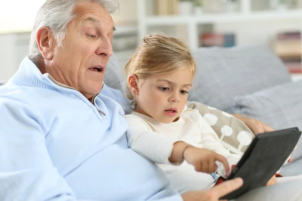 Девушка с дедушкой играет с цифровым планшетом — стоковое фото