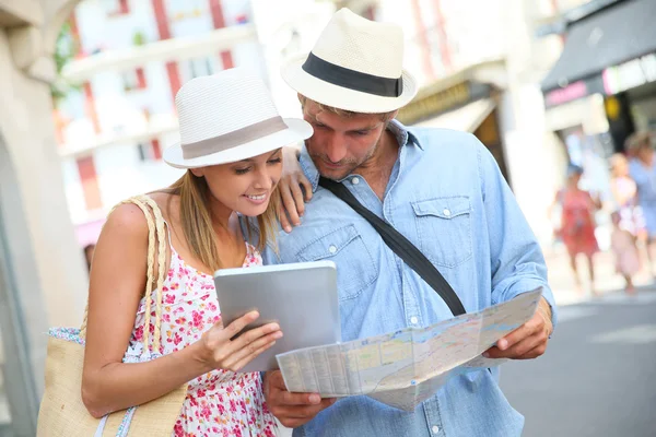 Couple in vacation looking at tourist guide — Stock Photo, Image