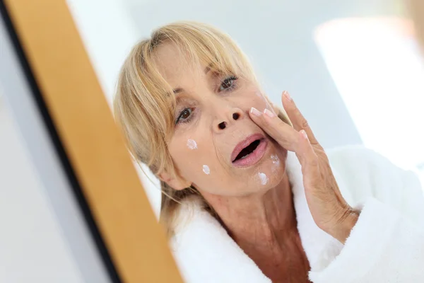 Mulher aplicando creme facial em sua pele Fotografia De Stock