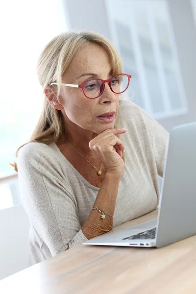 Mujer con gafas en el uso de la computadora portátil Imagen de archivo