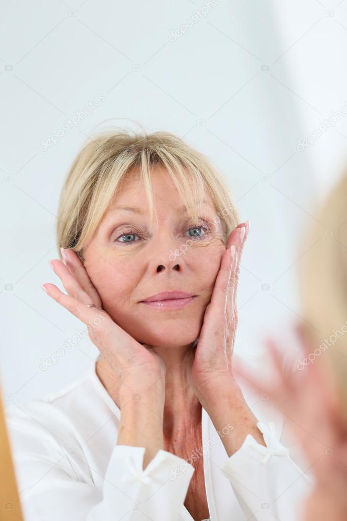 Senior woman looking at her skin