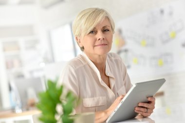 Tablet üzerinde çalışan üst düzey iş kadını