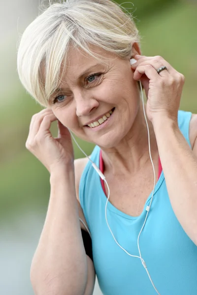 Mulher ajustando fones de ouvido — Fotografia de Stock