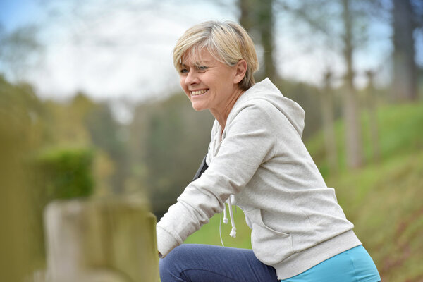 Старшая женщина растягивается после тренировки
