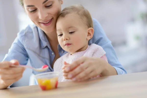 Madre ayudando a bebé niña con comer — Foto de Stock