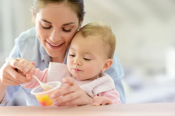 Madre ayudando a bebé niña con comer — Foto de Stock