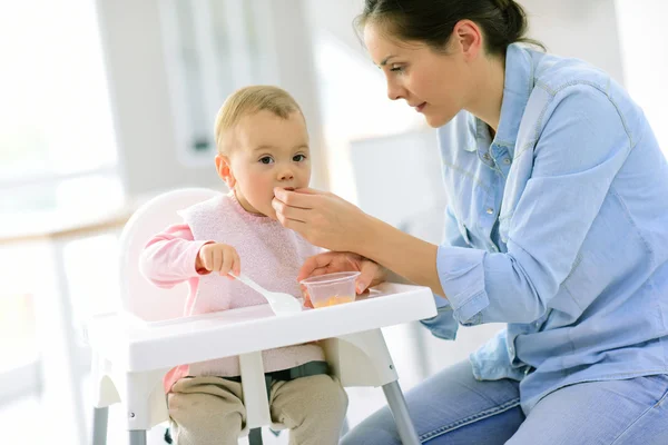 Menina bebê comendo em sua cadeira — Fotografia de Stock