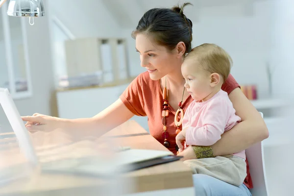 Femme travaillant avec bébé sur les genoux — Photo