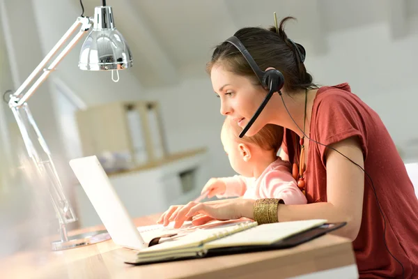 Business woman working with baby on lap — стоковое фото