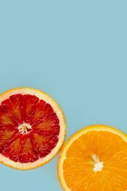 Modaya uygun mavi arka planda iki farklı portakal dilimi. Üst görünüm ve kopyalama alanı