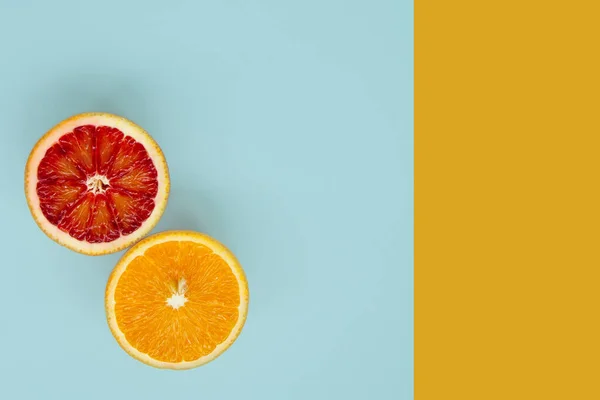 Two slices of red and yellow oranges  on blue and yellow background,top view and copy space