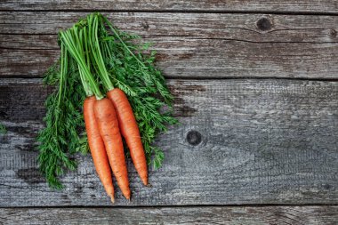 Kırsal ahşap arka planda üç lezzetli organik havuç, üst manzara.