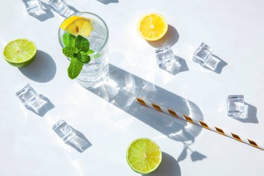Limon ve nane kokteyli ya da limonata, dokulu taş arka plan, üst manzara. İçkili bir bardak ve güneş ışığından gelen sert bir gölge. Yaz kompozisyonu.