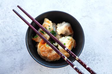 Kızarmış hamur köftesi ve Japon çubuğu ile siyah kase. Gri taştan arka planda Asya geleneksel yemeği, üst görünüm.