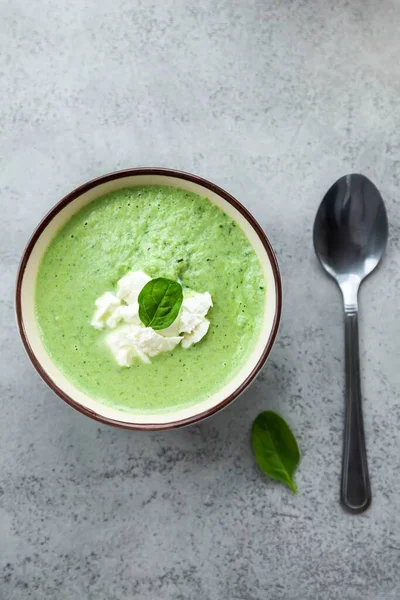 Yeşil kremalı çorba, gri bir masada mavi bir kasede. Yaz yemeği ya da akşam yemeği.