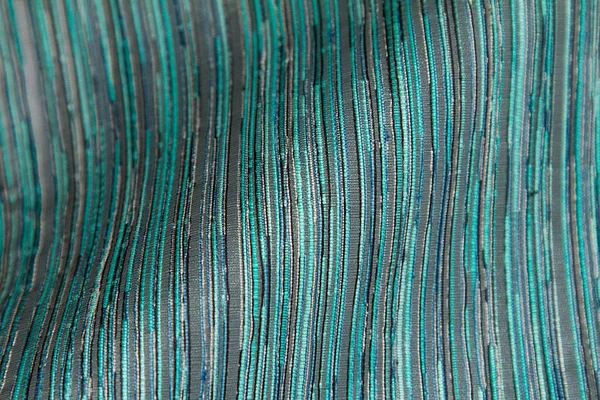 Fabric background with multicolored variegated thin strokes.Textile background made of blue,turquoise with thin stripes and threads.Abstract fabric style with a wave in the middle of the background