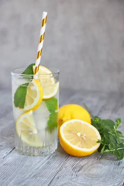 Limonlu buzlu limonata ve gri ahşap arka planda naneli dilimler. Yakın plan..