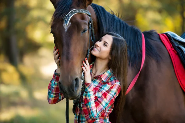 Mooi lang haar jonge vrouw poseren met een paard buiten Stockfoto