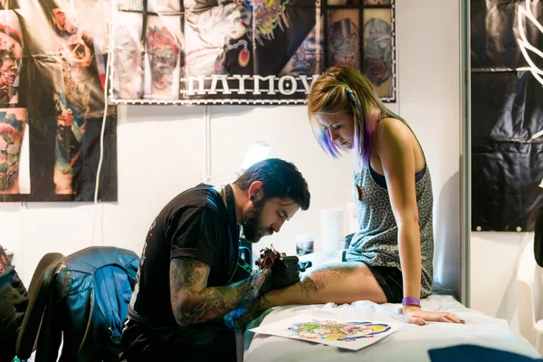 MINSK, BÉLARO - 19 de septiembre de 2015: Artista profesional del tatuaje haciendo tatuaje en una pierna de mujer . — Foto de Stock