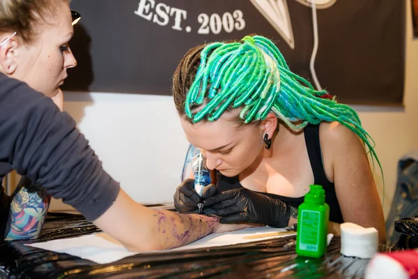 MINSK, BELARUS - SEPTEMBER 19, 2015: Professional tattoo artist doing tattoo on hand. — Stock Fotó