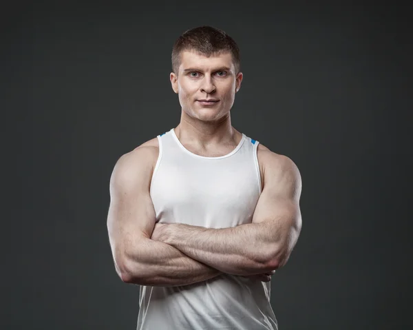 Młody człowiek mięśni na białym tle na szarym tle — Zdjęcie stockowe