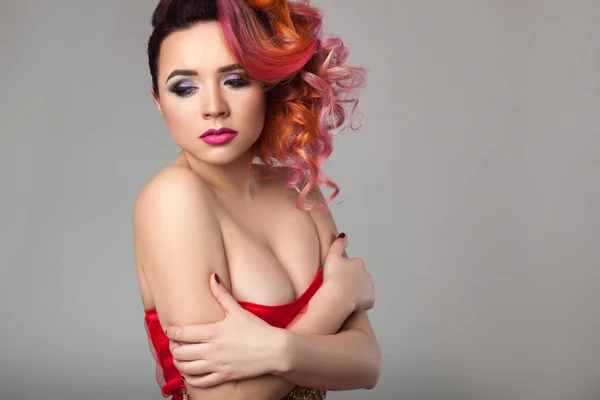 Menina bonita em vestido vermelho com cabelo encaracolado . Fotos De Bancos De Imagens