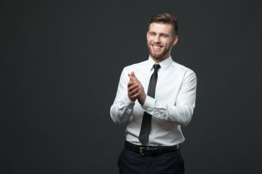 Genç mutlu yakışıklı işadamı elini çırpan stüdyo portresi