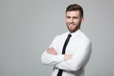 Gri arka planda yakışıklı genç işadamıportresi.