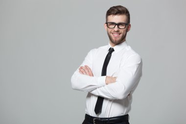 Gri arka planda yakışıklı genç işadamıportresi.