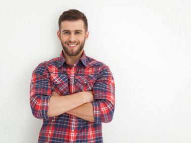 Yakışıklı genç adam ayakta beyaz duvara karşı.
