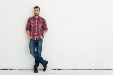 Yakışıklı genç adam ayakta beyaz duvara karşı.