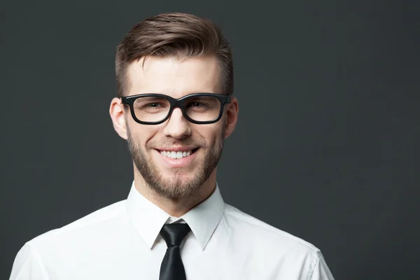 Young handsome businessman thinking on dark gray background. — Stockfoto