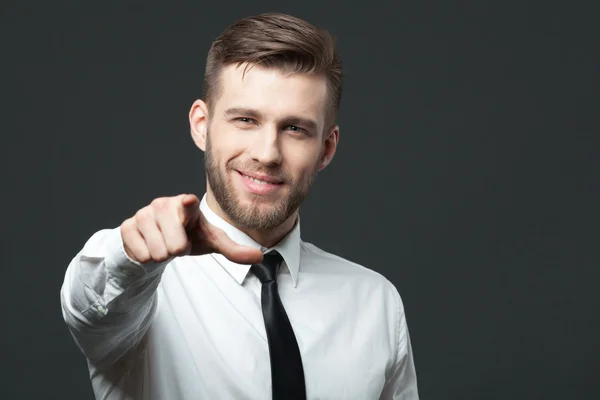 Joven hombre de negocios guapo apuntando a usted aislado en gris bac — Foto de Stock