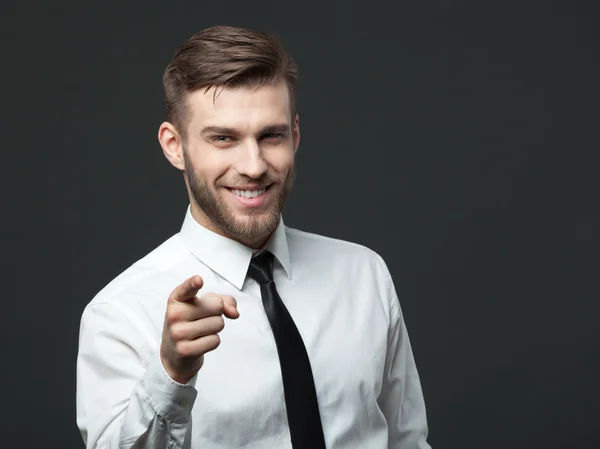 Joven hombre de negocios guapo apuntando a usted aislado en gris bac — Foto de Stock