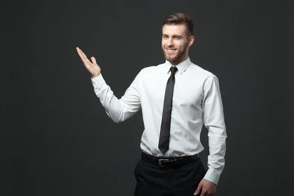 Bonito jovem empresário segurando seu braço para cima apresentando copyspa — Fotografia de Stock