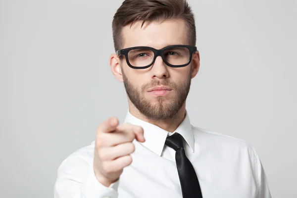 Joven hombre de negocios guapo apuntando a usted aislado en gris bac — Foto de Stock