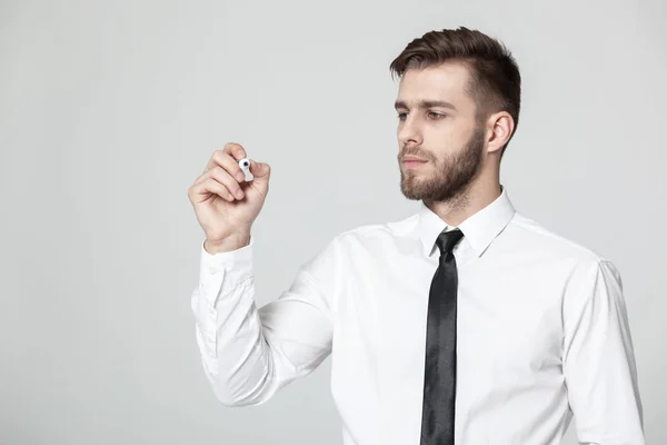 Jovem empresário bonito escrevendo em um painel transparente . Fotografia De Stock